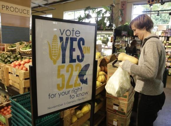 A customer picks up produce near a sign supporting a ballot initiative in Washington state that would require labelling of foods containing genetically modified crops at the Central Co-op in Seattle, Washington October 29, 2013. CREDIT: REUTERS/JASON REDMOND 